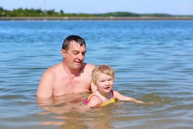 Küçük kızı sıcak güneşli bir günde gölde yüzme ile etkin baba