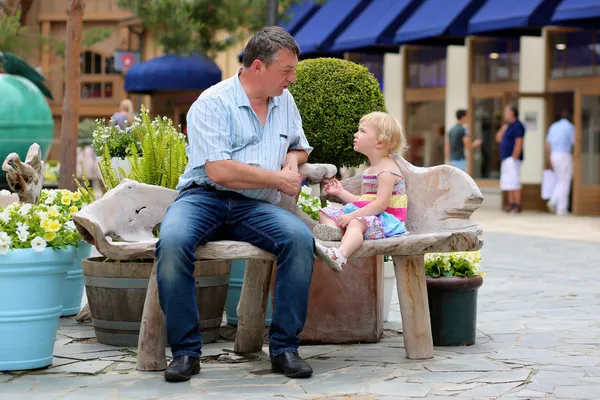 Father and daughter relaxing on the bench in urban setting — Stock Photo, Image