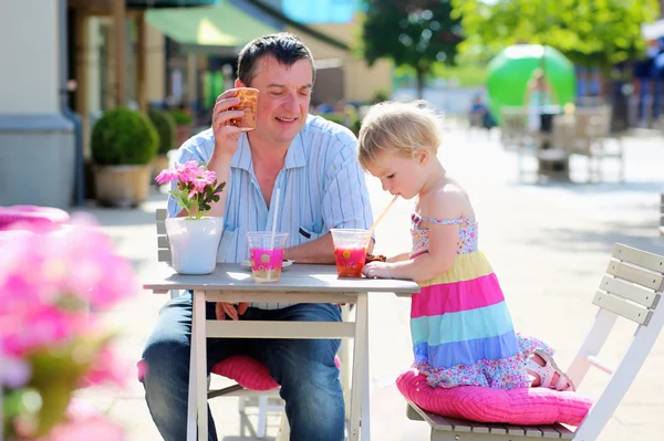 Father and little daughter drinking and eating in outdoors cafe — Stock Photo, Image