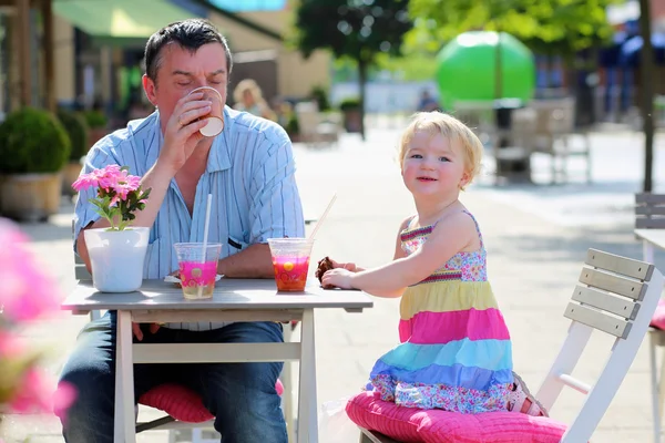 Otec a dcera malá, pití a jídlo v přírodě café — Stock fotografie