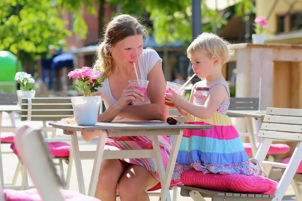 Mladá matka a malá dcera užívat letní nápoje v kavárně venku — Stock fotografie