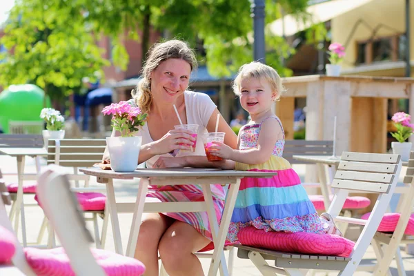 Junge Mutter und kleine Tochter genießen sommerliche Drinks im Café im Freien — Stockfoto