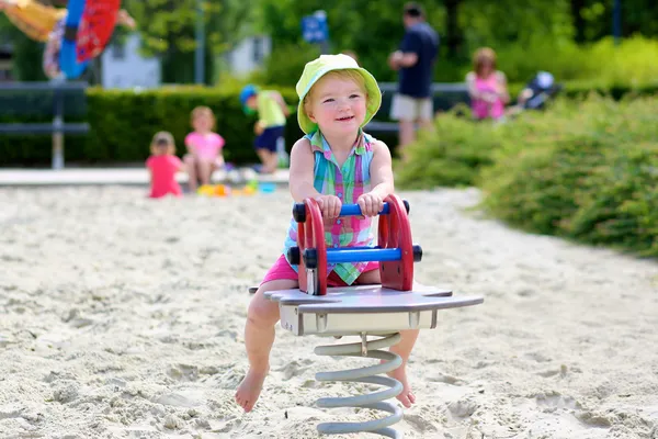 Lilla tjejen njuter av sommardag på lekplatsen studsande på våren häst — Stockfoto