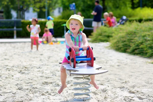 Klein meisje genieten van zomerdag op de speelplaats stuiteren op lente paard — Stockfoto