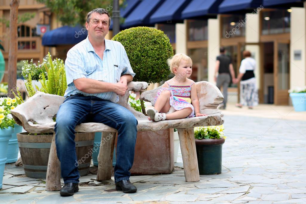 Father and daughter relaxing on the bench in urban setting