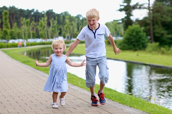 Šťastné děti běží společně u malé řeky — Stock fotografie