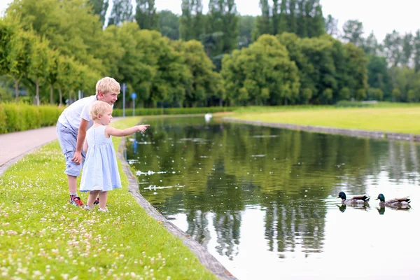 Zwei Kinder füttern Enten in kleinem Teich — Stockfoto