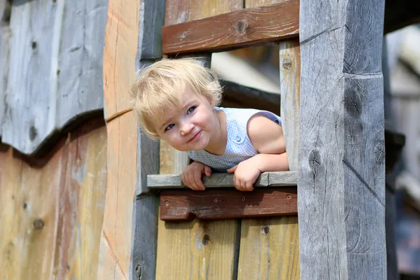 Забавная маленькая девочка играет в деревянном доме — стоковое фото
