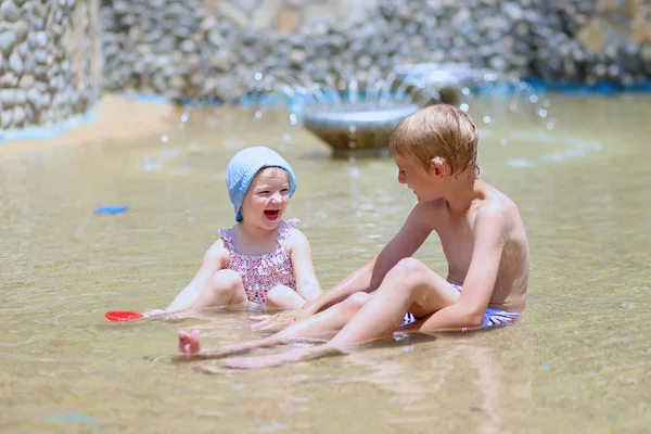 Hermano y hermana divirtiéndose jugando con agua y arena — Foto de Stock