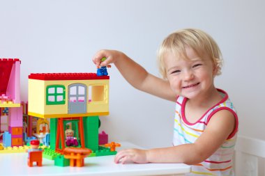 mutlu küçük kız ev renkli plastik bloklarla inşa