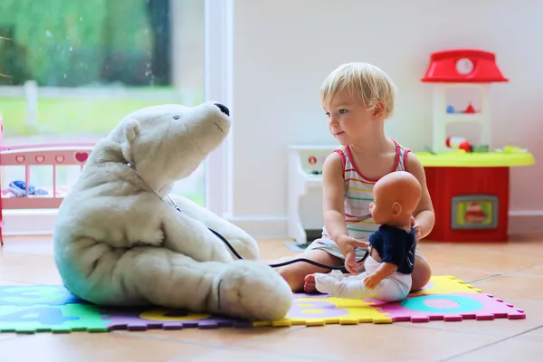 Kleines Mädchen spielt Arzt, der Teddybär versorgt — Stockfoto