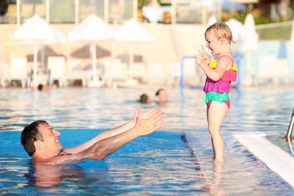 Father and daughter having fun in outdoors swimming pool
