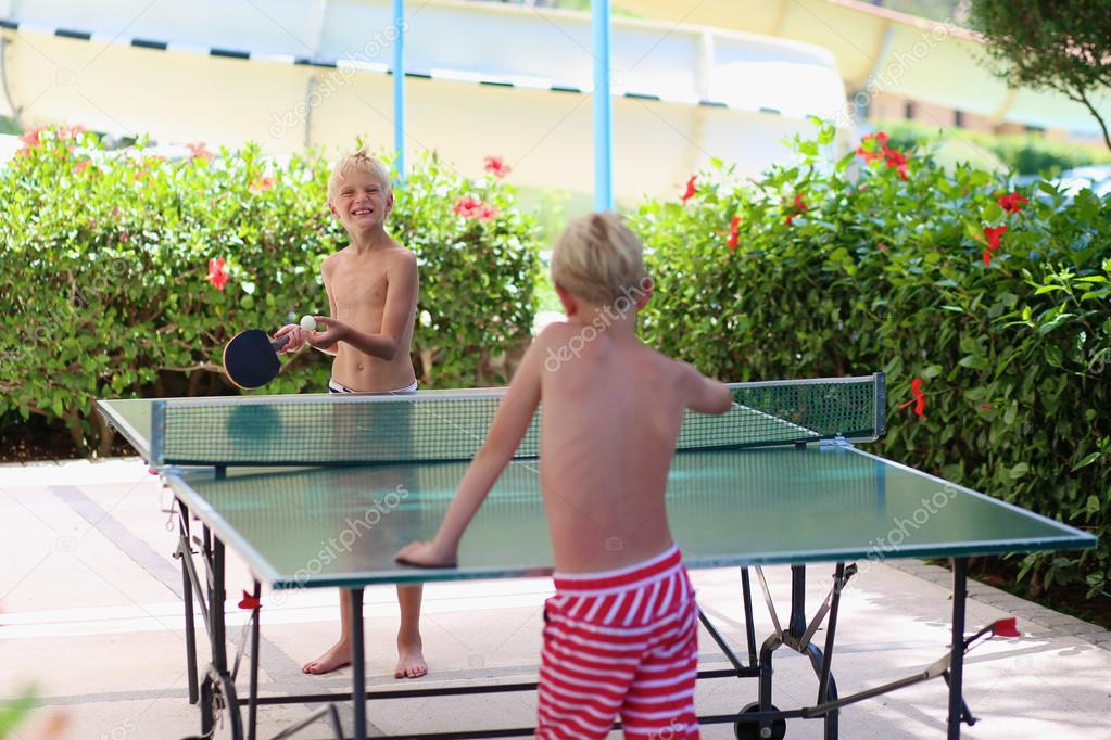 Two happy boys playing ping pong outdoors