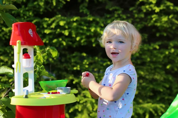 Glada barnet flicka som leker med leksak kök utomhus — Stockfoto