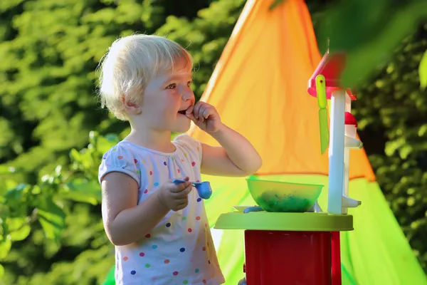 Ευχαρίστως toddler κορίτσι παίζει με παιχνίδι κουζίνα σε εξωτερικούς χώρους — Φωτογραφία Αρχείου