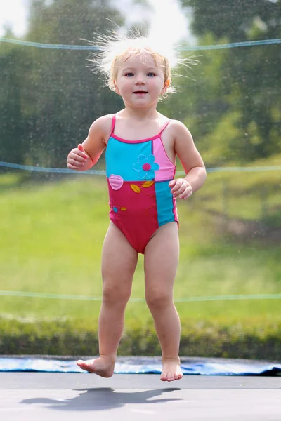 Funny little girl jumping on trampoline — Stock Photo, Image