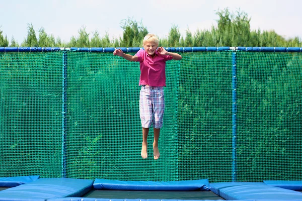 Gelukkig school jongen springen op de trampoline — Stockfoto