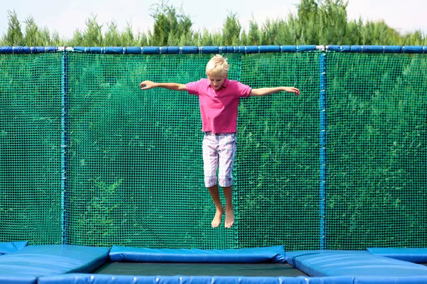 Felice scuola ragazzo jumping su trampolino — Foto Stock