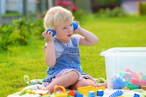 Engraçado menina brincando com brinquedos ao ar livre — Fotografia de Stock
