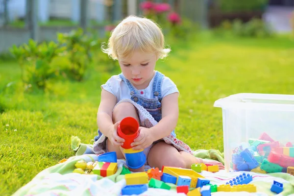 Забавная маленькая девочка играет с игрушками на открытом воздухе — стоковое фото
