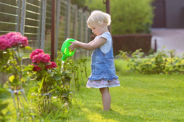 Schattig peuter meisje drenken bloemen in de tuin — Stockfoto