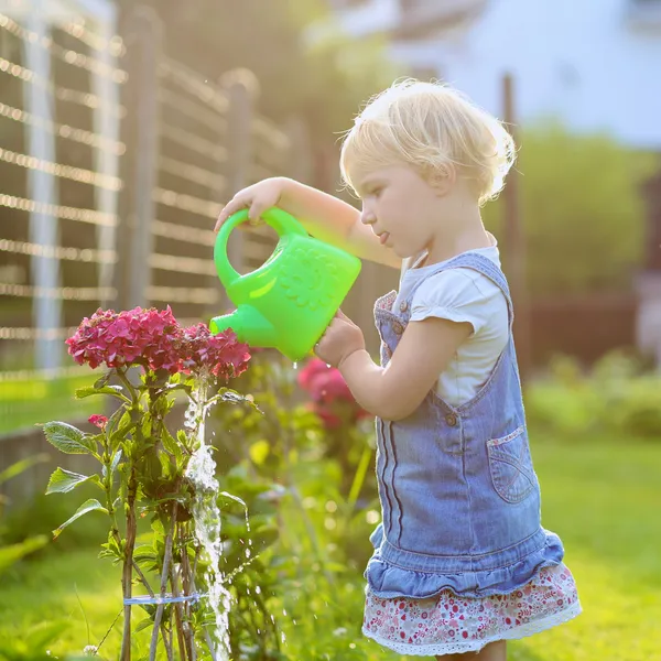 Linda niña regando flores en el jardín —  Fotos de Stock