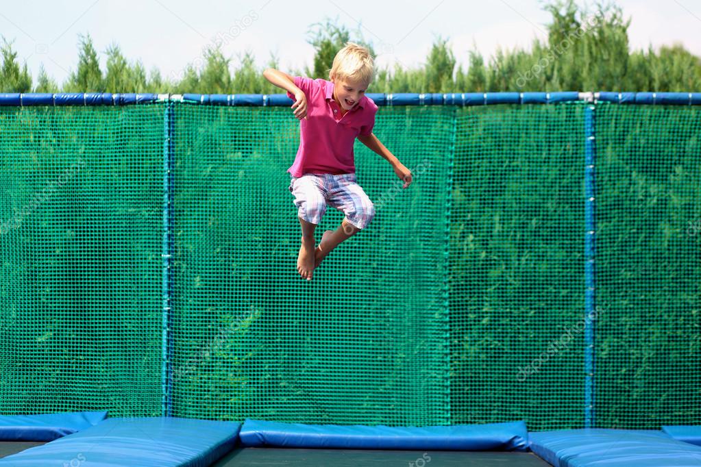 Happy school boy jumping on trampoline