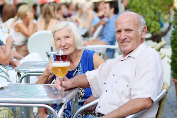 Senior couple drinking beer in outdoors cafe — Stock Photo, Image