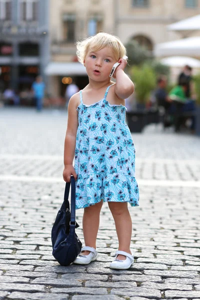 Cute little girl talking on mobile phone in the middle of the city — Stock Photo, Image