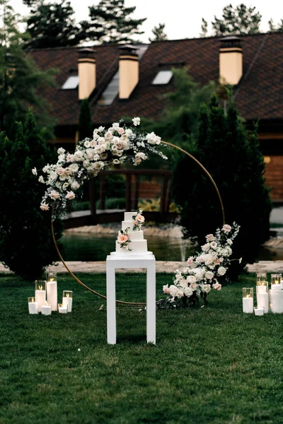 Düğün pastası. İştah açıcı beyaz pasta bej bir masada dört kat, güllerle süslenmiş, okaliptüs, açık yeşil arka plan