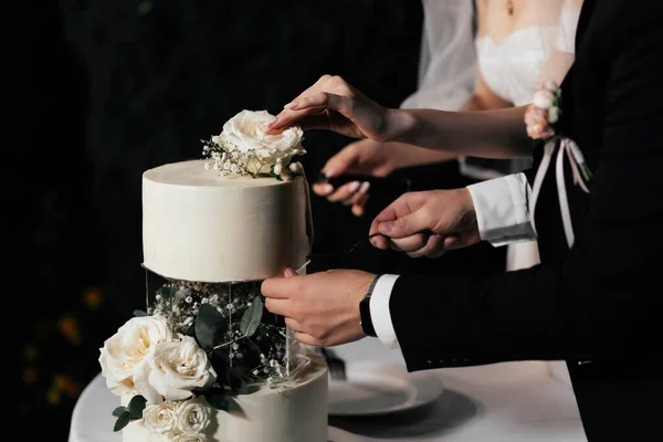 结婚蛋糕 乳白色的蛋糕 装饰着美丽的玻璃杯装饰 装饰着玫瑰 桉树和深色背景的花朵 — 图库照片
