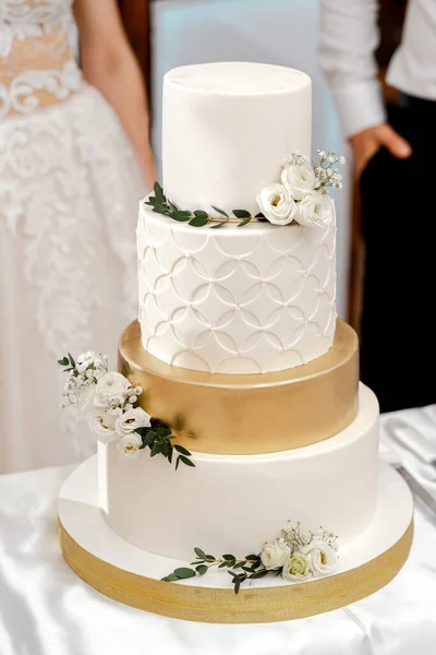 wedding cake white three tiers on a dark background with white and yellow roses gold edging