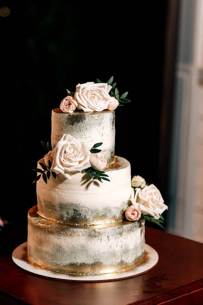 Düğün pastası. Üç kat zemin. Beyaz altın çiçekler.