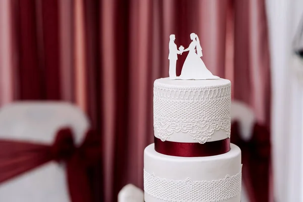 wedding cake white cream mastic four floors with red ribbons bow with newlyweds from above white background