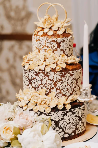 wedding cake Ukrainian three floors flowers from flour decor roses wedding rings on a beige background