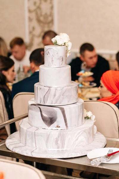 large wedding cake many tiers floors white marble cream flowers roses stand on white wedding decor