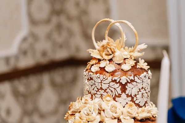 wedding cake Ukrainian three floors flowers from flour decor roses wedding rings on a beige background