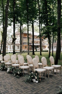 Düğün ziyafeti. Masa örtülü kutlama masaları çiçek kompozisyonlarıyla süslenir, masalarda peçeteli tabaklar, bardakta mumlar