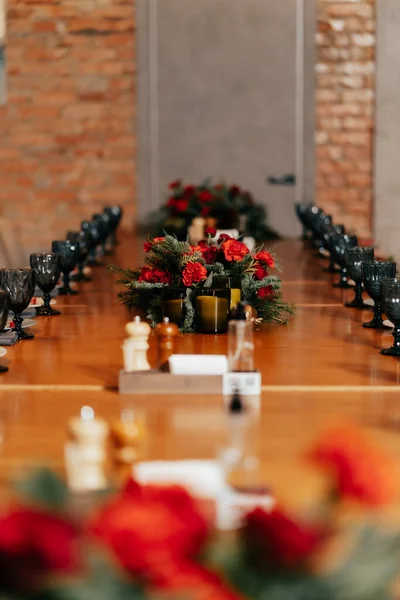 Çatı katı tarzı bir restoranda gözlüklerle servis edilen uzun bir masa, sıcak ışıklandırmalı tabaklar ve tablolarla servis edilir.