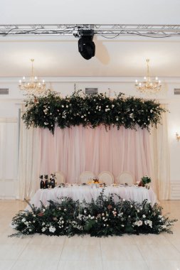 Çiçeklerle, yeşilliklerle, güllerle, orkidelerle süslenmiş güzel pembe ve bej tonlarda bir restoran.