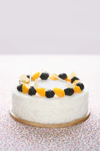 Coconut & Marshmallow Cake with coconut flakes, blackberries and pieces of peach