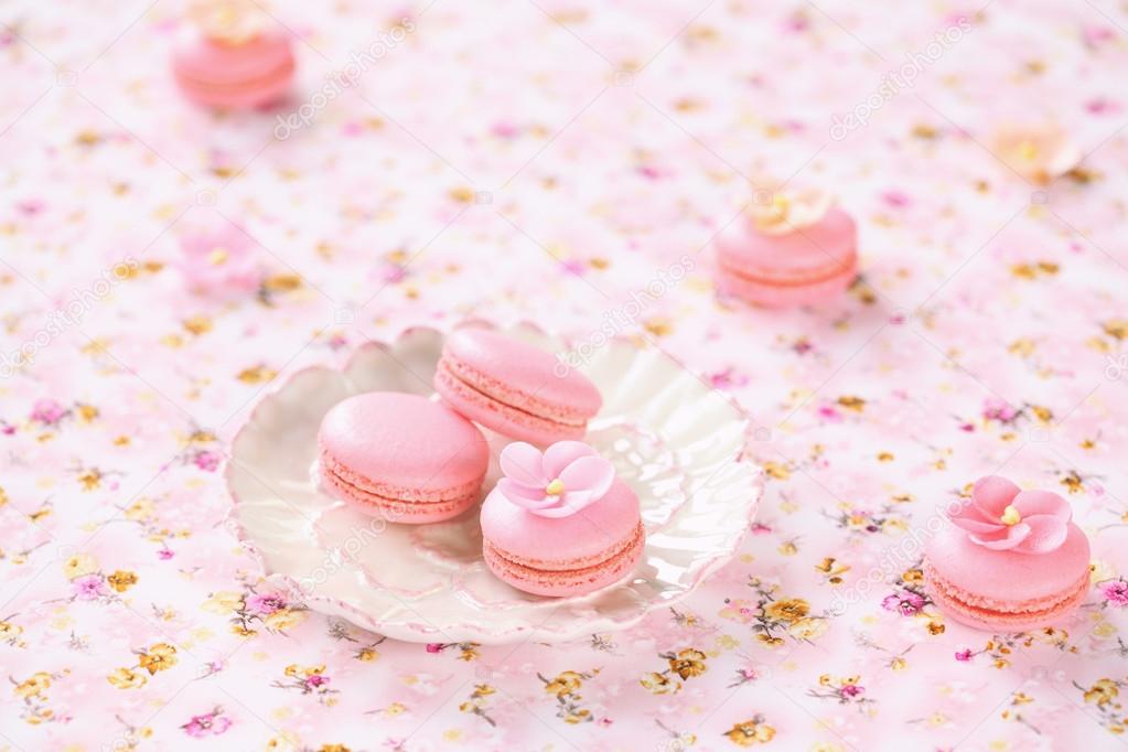 Pink Macarons on white plates, on a light pink floral tablecloth