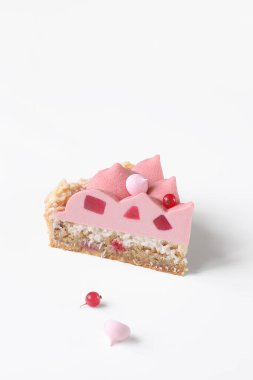 Çağdaş kırmızı frenk üzümü ve hindistan cevizli tart, yakut çikolata kadife kaplama, pembe kremalı kurabiyelerle süslenmiş, beyaz arka planda..