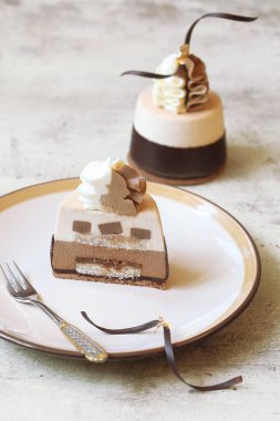 Çağdaş Kahve Çikolatalı Mini Mousse Kekleri, çikolataya batırılmış, çırpılmış beyaz ve sütlü çikolatayla süslenmiş, ve çikolatalı spiraller, açık arkaplanda..