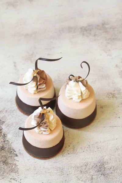 Çağdaş Kahve Çikolatalı Mini Mousse Kekleri, çikolataya batırılmış, çırpılmış beyaz ve sütlü çikolatayla süslenmiş, ve çikolatalı spiraller, açık arkaplanda..