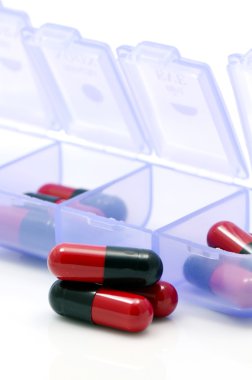 oral ilaç kapsül ayrılmış birim doz kutusunda beyaz zemin üzerine kırmızı ve siyah.