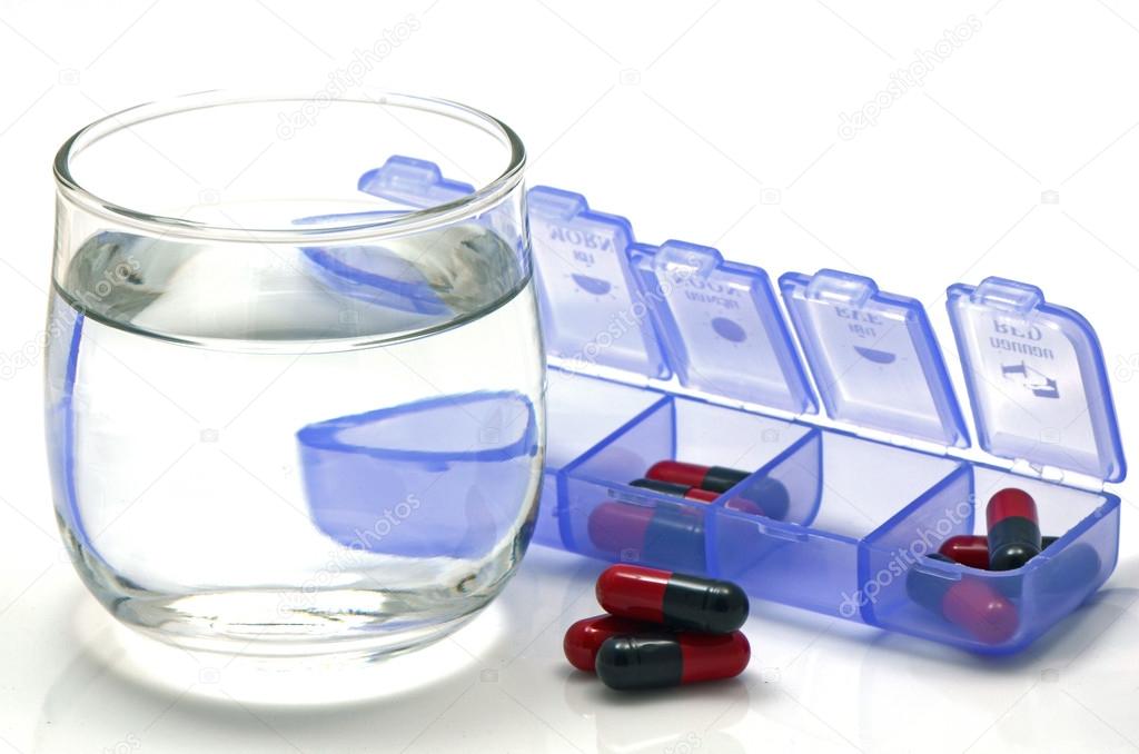Oral medication red and black capsules in separated unit-dose box on white background.