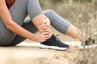 Close up of a runner suffering ankle lesion after sport in the mountain clipart