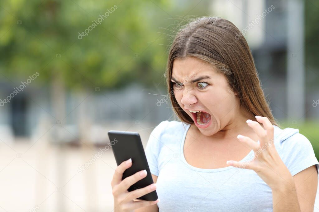 Angry teen watching media on smartphone in a park