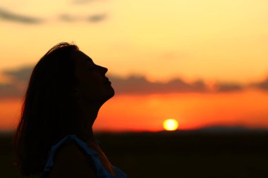 Güneş doğarken temiz hava soluyan bir kadının arka plan görüntüsü.